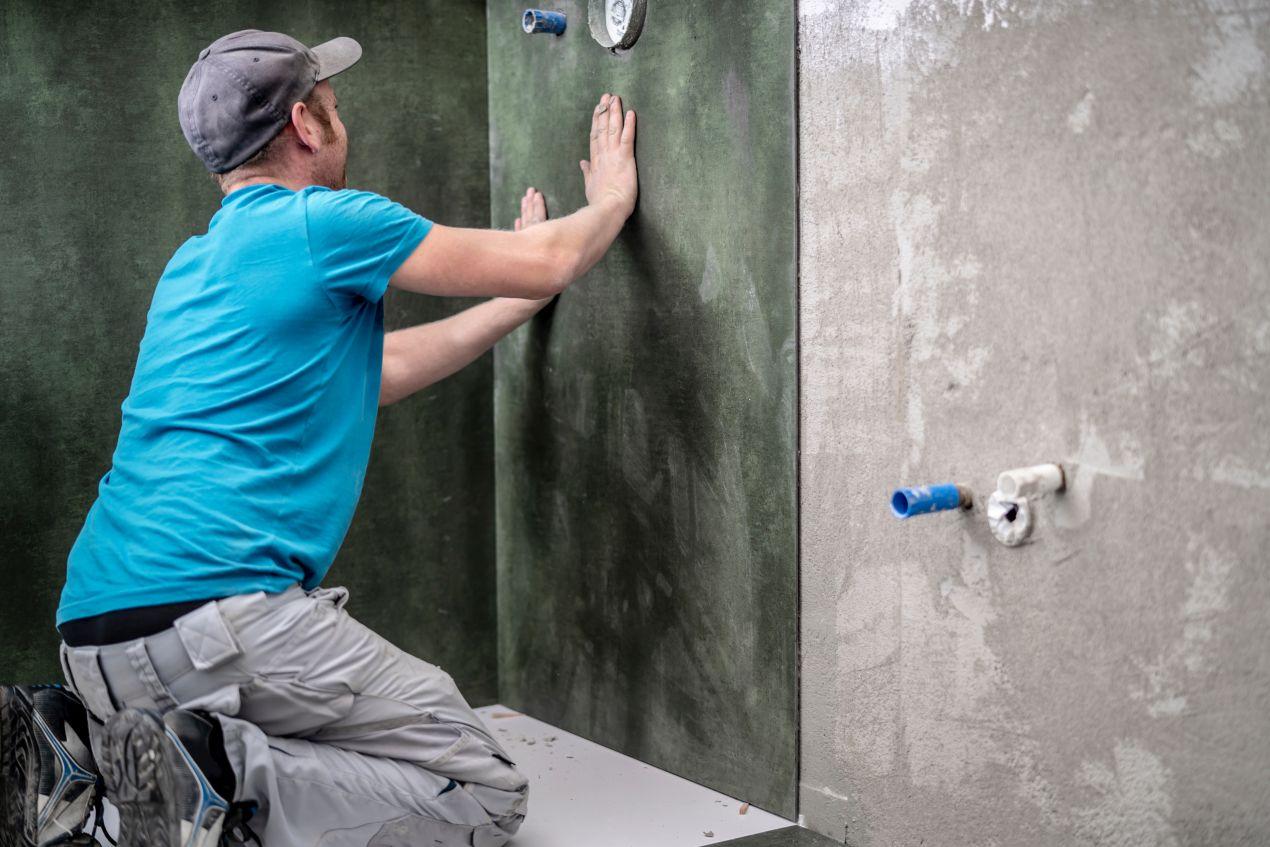 Handwerker montiert grüne Duschrückwand Platten in Betonoptik in einem Badezimmer