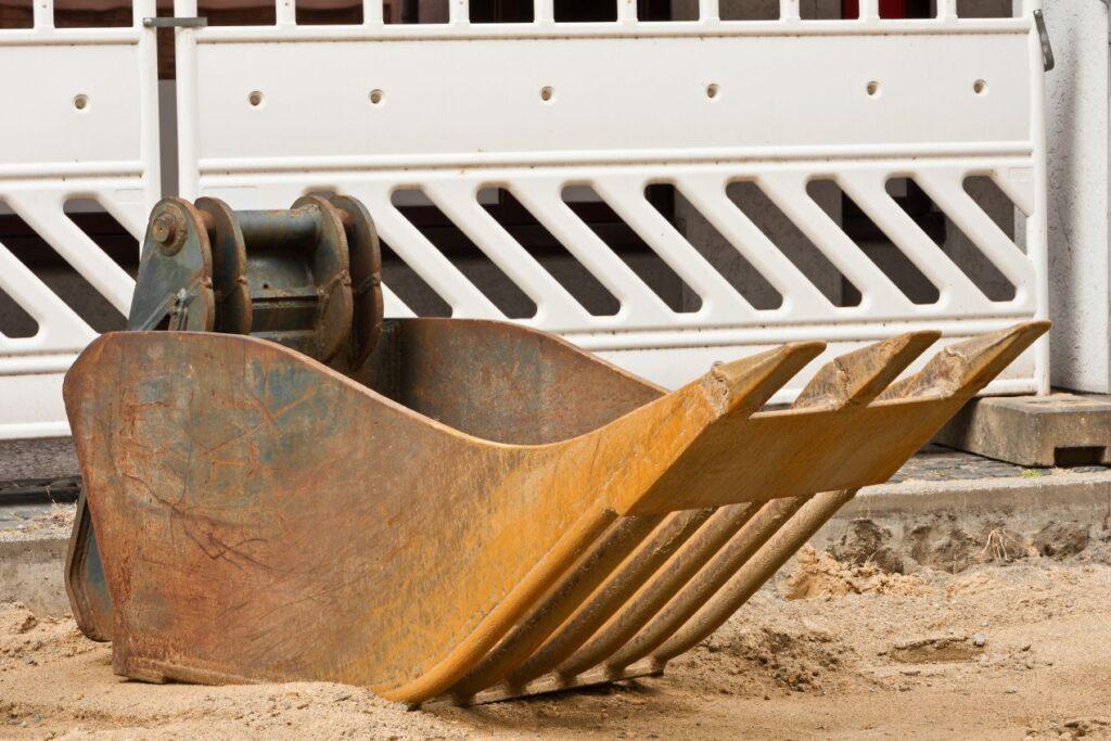 Minibagger Schaufel mit Zähnen auf Baustelle, bereit für Aushubarbeiten bei dichtem Untergrund